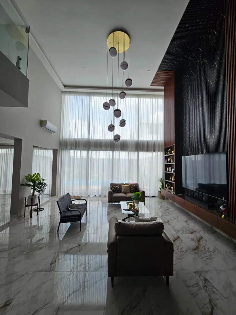 Cortinas traslúcidas en una sala a doble altura con muro oscuro