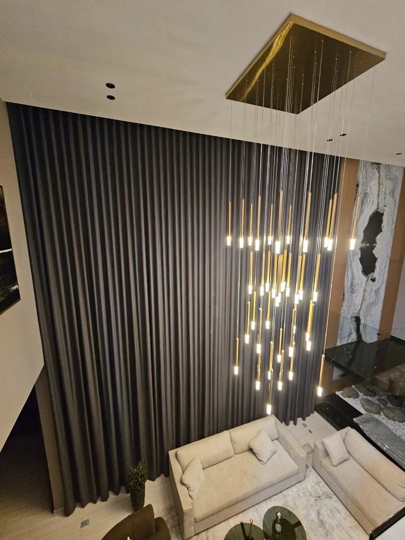 Cortinas oscuras en confección onda perfecta junto a una lámpara dorada