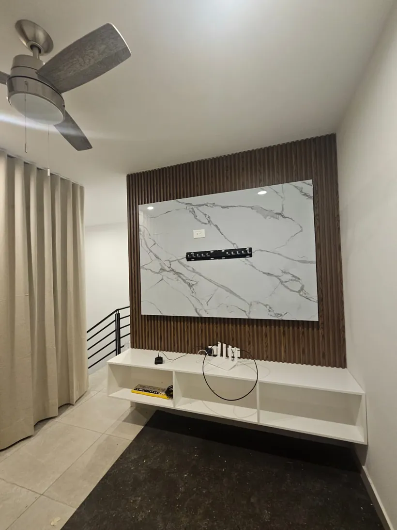 Muro de televisión con lambrín de madera y placa de PVC tipo mármol